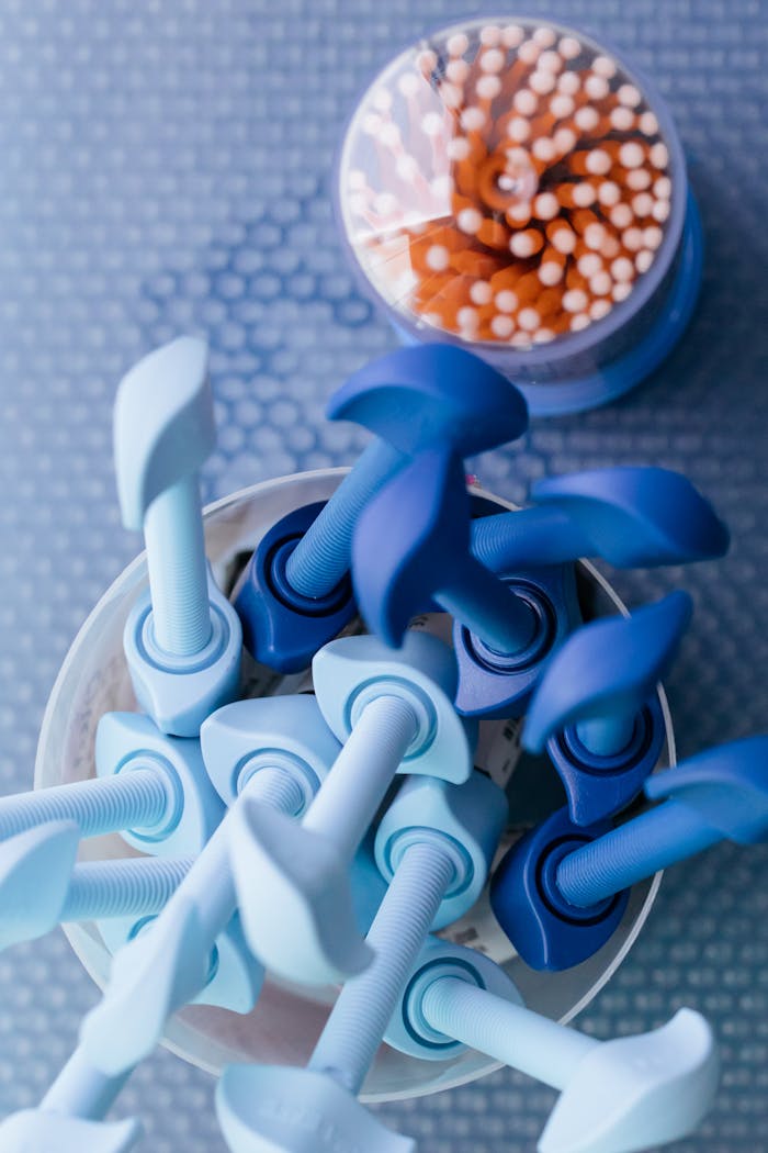 Overhead view of blue dental equipment tools with cotton swabs in the background.